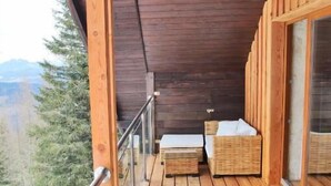 A wooden deck with two wicker lounge chairs and a small table, overlooking a mountainous landscape. - Alpengasthof Krische (Sankt Georgen am Kreischberg)