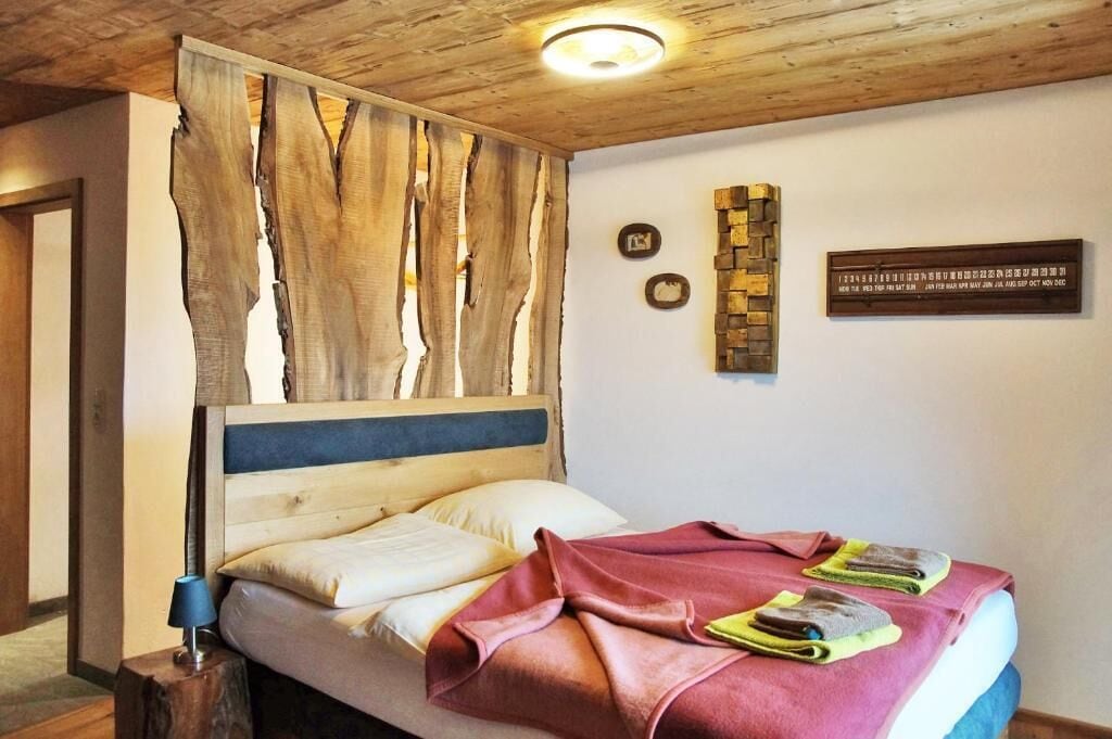 A bedroom with a wooden headboard, a bed with pillows, a bedside table with a lamp, and a wall with two plaques.