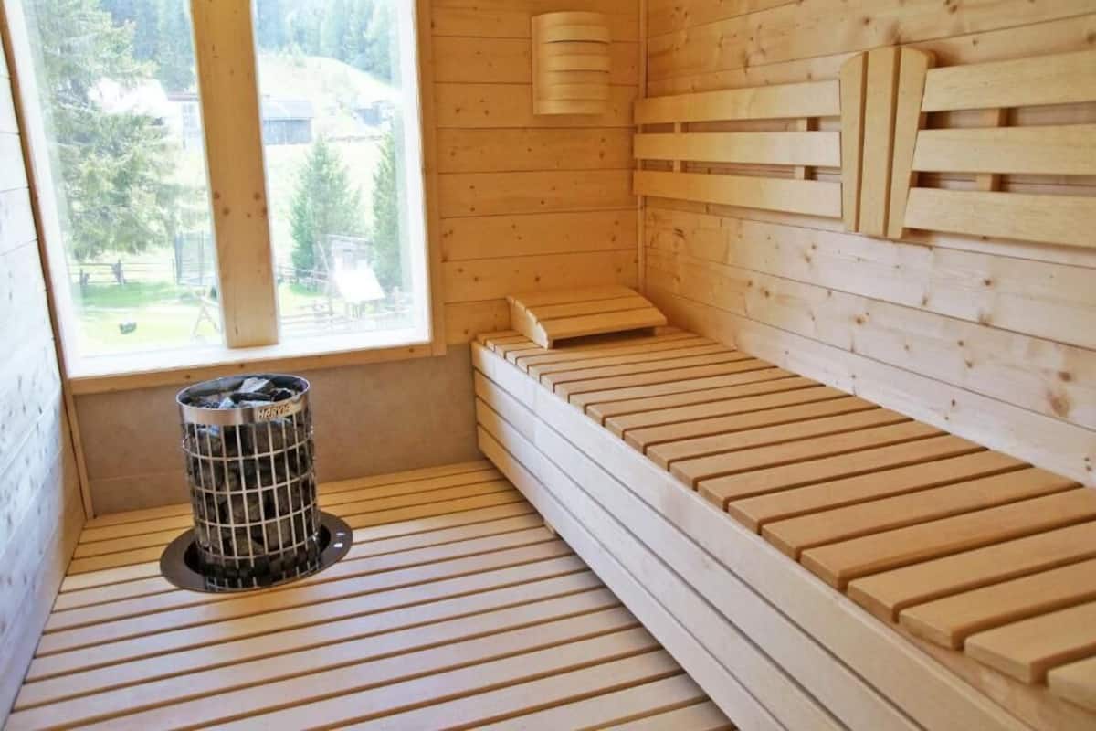 Ein Saunaraum mit Holzbänken, einem Fenster und einem Mülleimer.