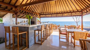 A beachside bar with wooden furniture and a view of the ocean. - Nalika Beach Resort & Restaurant - Adults Only (Seririt)