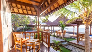 A wooden deck with outdoor furniture, a pool, and a view of the sea. - Nalika Beach Resort & Restaurant - Adults Only (Seririt)