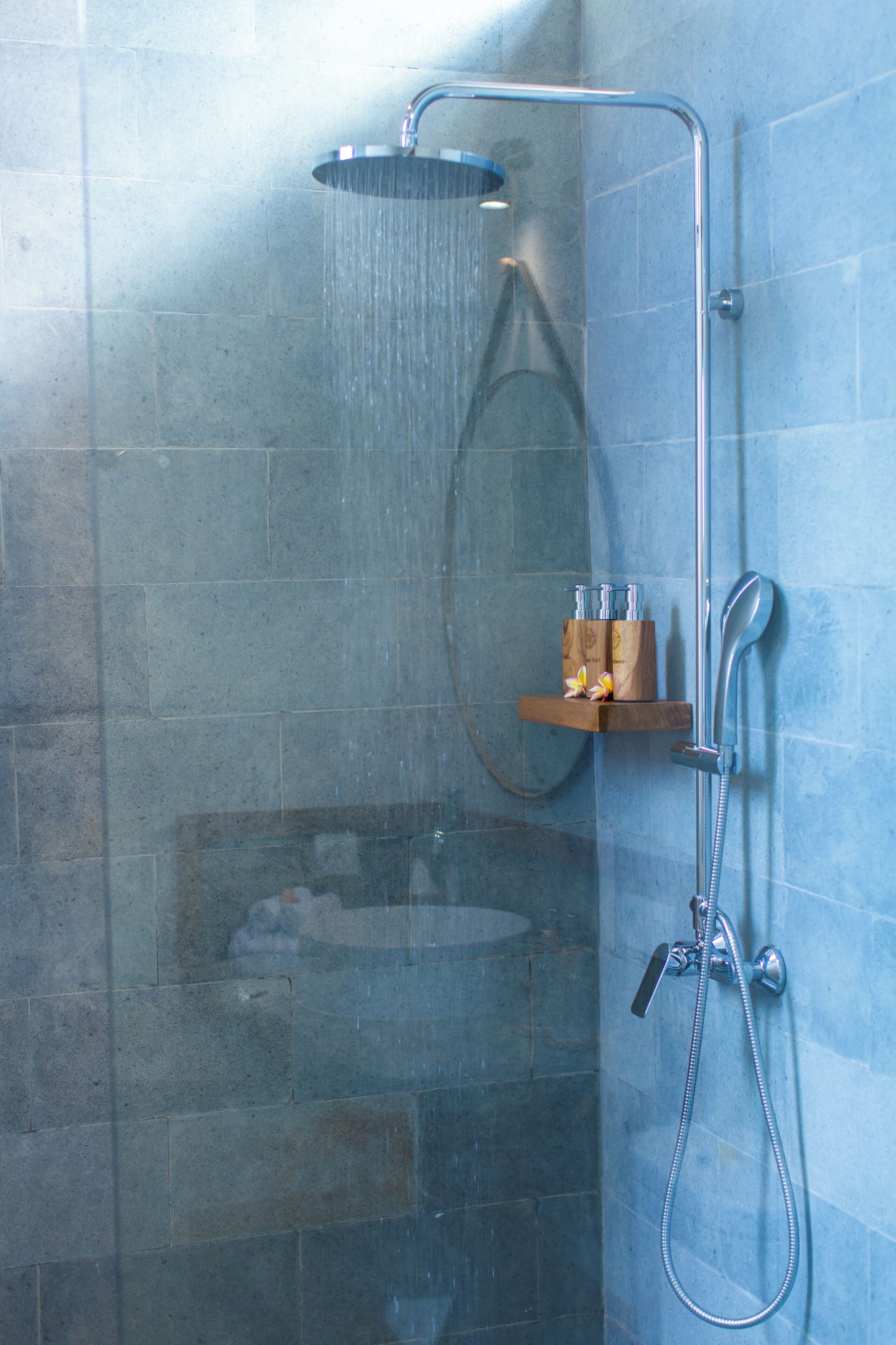 Eine Duschkabine mit Handbrause und am Wand montiertem Wasserhahn.