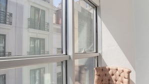 A balcony with a cushioned chair, a small table with a fruit bowl, and a glass of water.