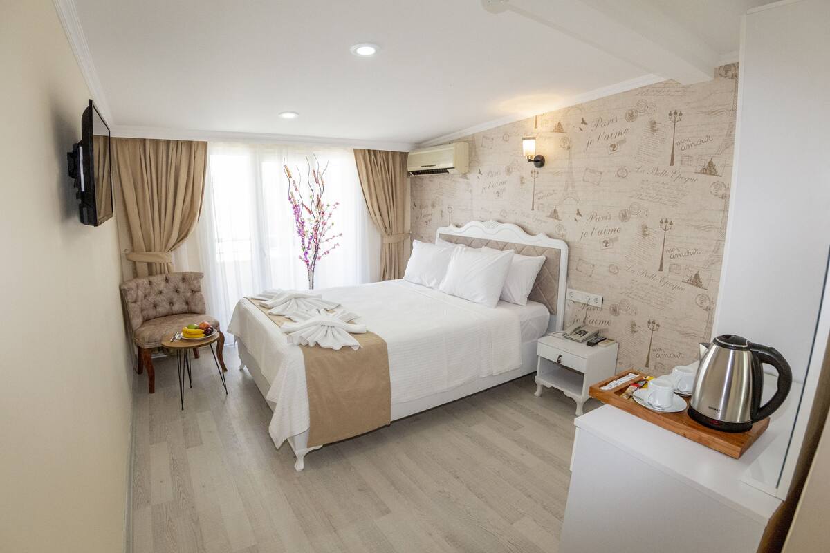 A hotel room with a large bed, a chair, a small table with a tray, and a coffee maker.