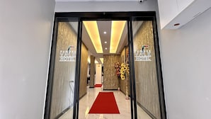 A hotel entrance with a red carpet, a chandelier, and a reception desk.