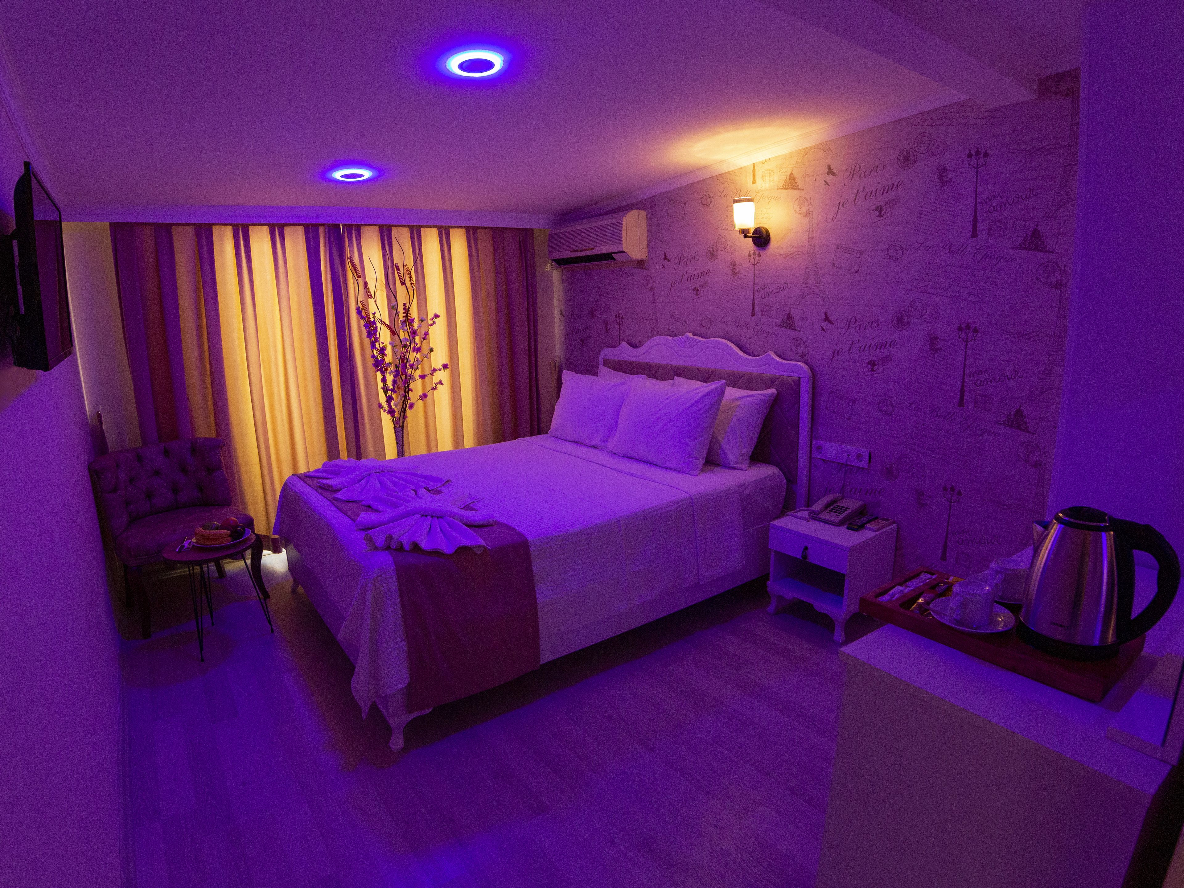 A hotel room with a bed, a chair, a nightstand, and a coffee maker.