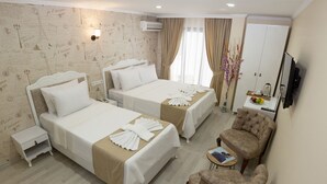 A hotel room with two beds, a sitting area with a chair, a small table, and a wardrobe.