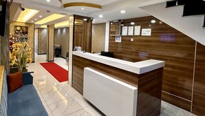 A modern reception area with a marble floor, a reception desk, and a blue sofa with orange cushions.