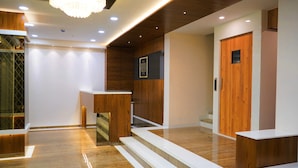 A modern hotel lobby with wooden accents, a reception desk, and a staircase. - Hotel Royal Treat (Surat)