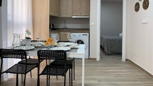 A compact kitchen with wooden cabinets, a washing machine, and a dining area with a table set for four. - GBH Hotel-Apartamentos Caballito de Mar (Benidorm)