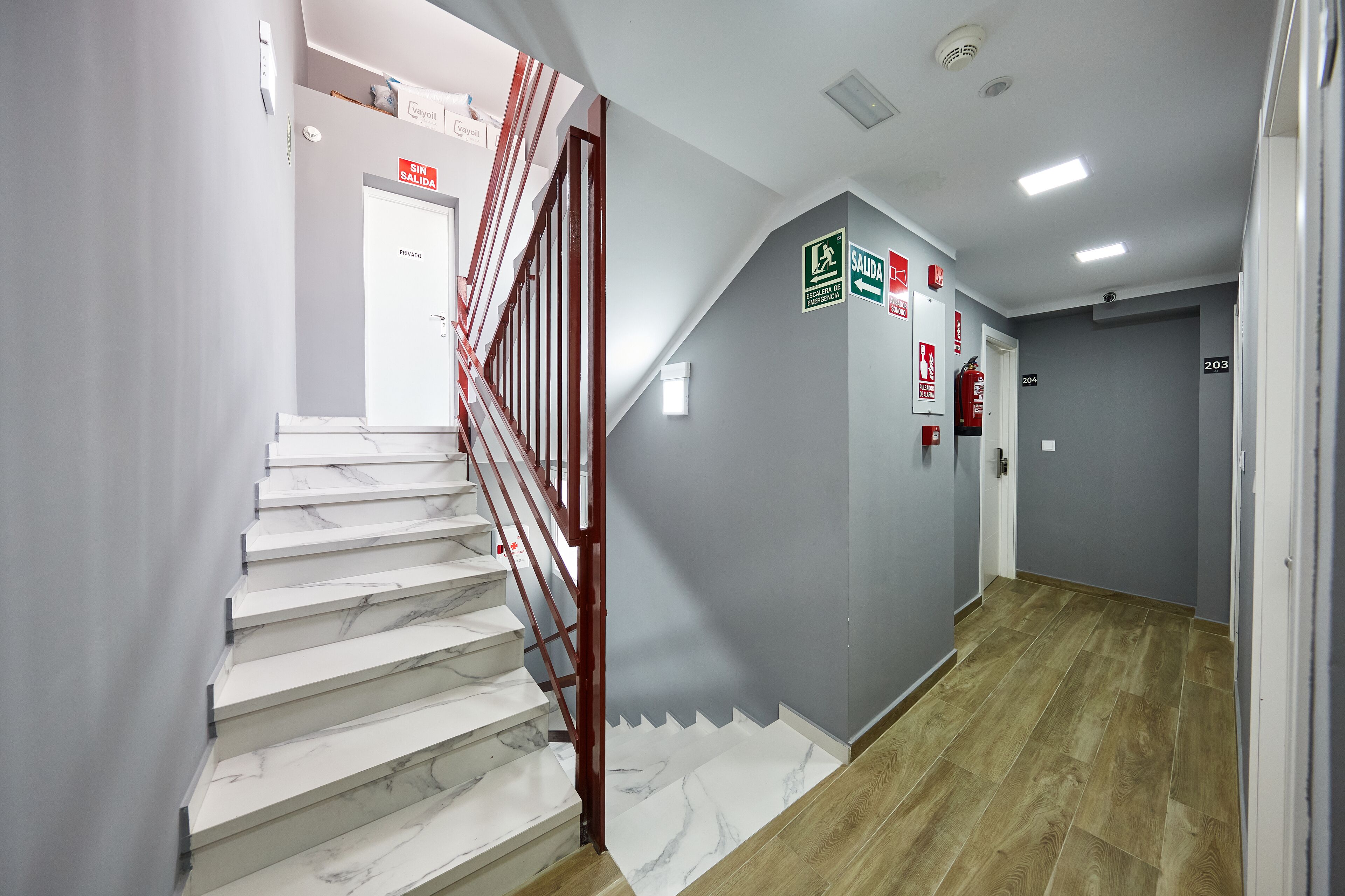 A staircase with marble steps and a red handrail, leading to a door marked "SAUDA."