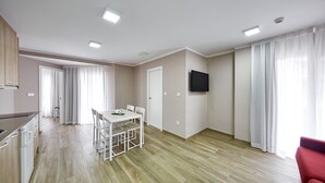 A spacious living area with a dining table, a kitchen with a dishwasher, and a flat-screen TV mounted on the wall. - GBH Hotel-Apartamentos Caballito de Mar (Benidorm)