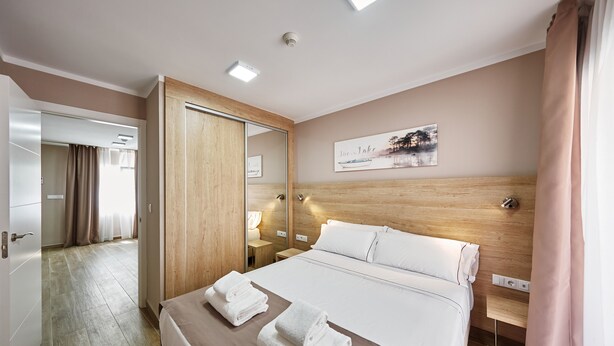 A hotel room with a large bed, a wooden headboard, a bedside table, a mirror, and a painting on the wall. - GBH Hotel-Apartamentos Caballito de Mar (Benidorm)
