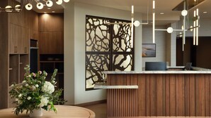 Un área de recepción moderna con un mostrador de madera, un panel decorativo en la pared y una lámpara colgante.