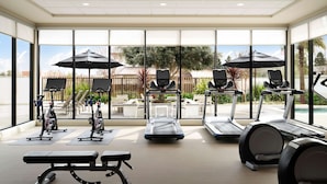 Un gimnasio con cintas de correr, elípticas y bancos.