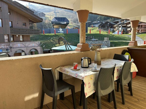A balcony with a table set for two, overlooking a mountainous landscape with a ski lift and chalets. - Bourg-Morel 2 - Large cosy duplex, balcony facing south, in the main pedestrian street (LES AVANCHERS VALMOREL)