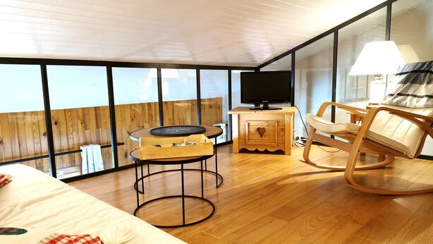Een gezellige kamer met een bed, een houten bureau met een televisie, een schommelstoel en een klein tafeltje met dienblad.