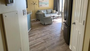 Un espacio habitable compacto con kitchenette, un sofá, una mesa de centro y un cuadro en la pared.