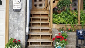 Un escalier en bois mène à une véranda où est affiché un panneau indiquant : « Bienvenue chez vous, au bord de la mer. »