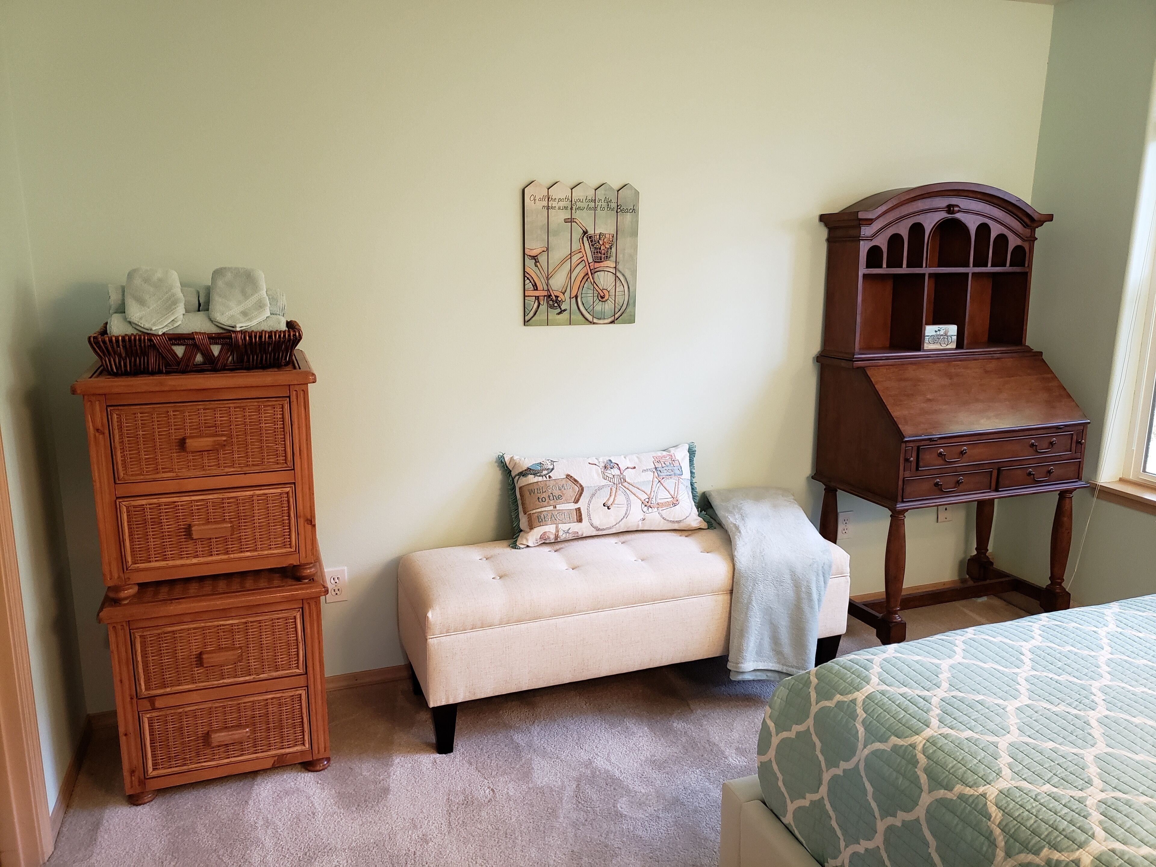 Une chambre à coucher comprenant un lit, un banc, une commode et un élément décoratif mural.