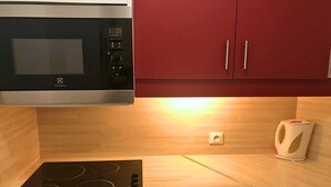 Una cucina con forno a microonde, fornelli e pensili rossi.