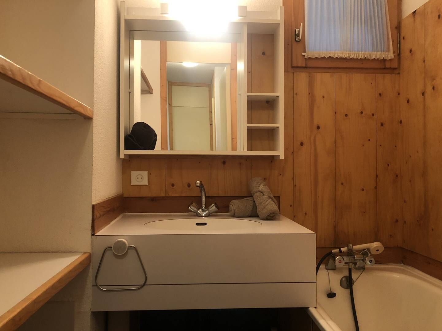 A bathroom with a white sink, a mirror, a towel rack, and a bathtub.