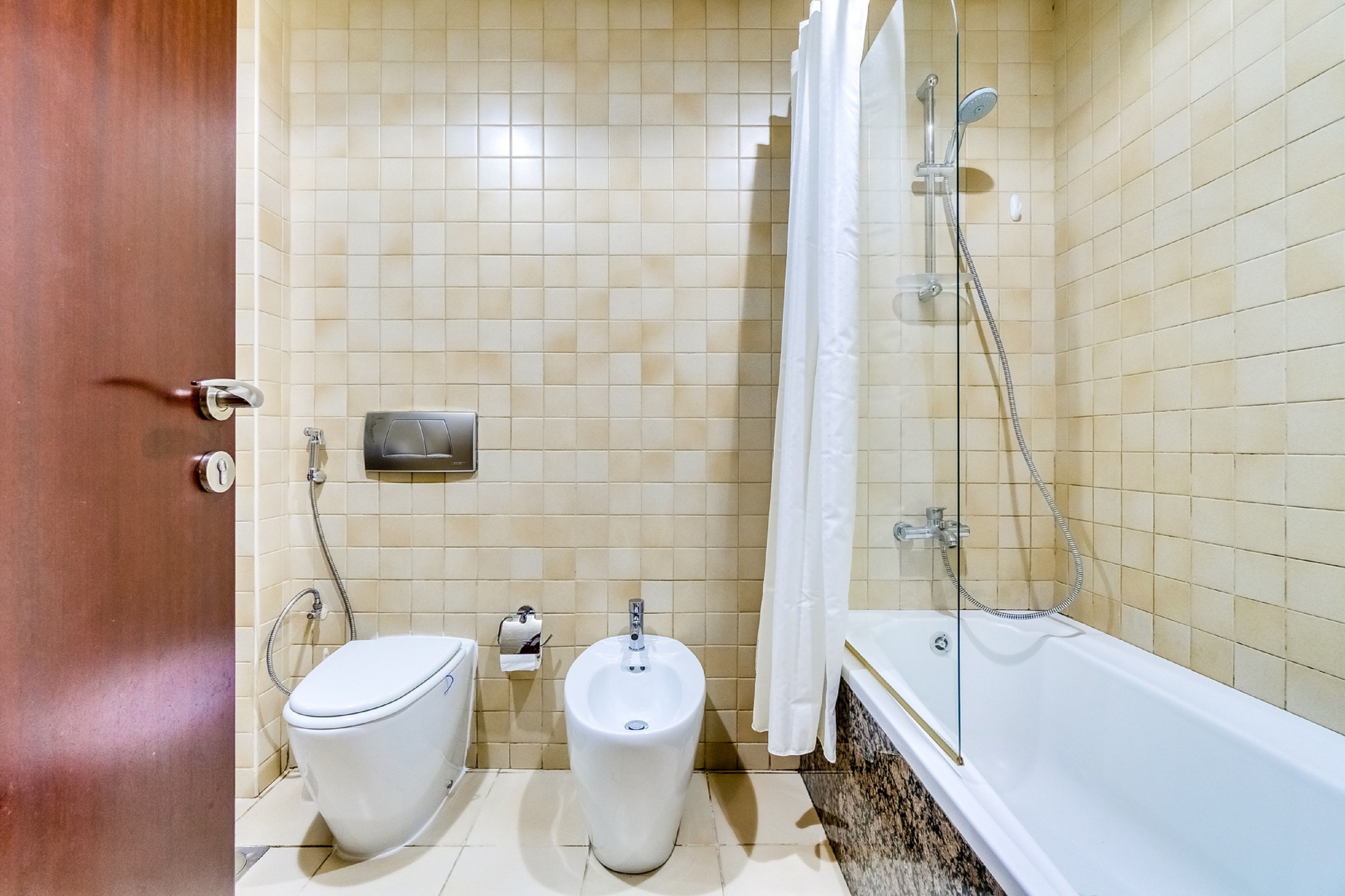 A bathroom with a toilet, bidet, and bathtub.