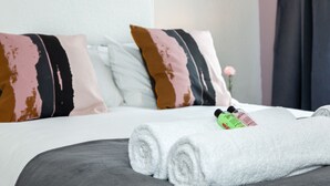 A neatly made bed with a rolled white towel and two bottles of lotion on it. - Cosy Home Near Station, Parking, Netflix, Sleeps 5 (Coventry)