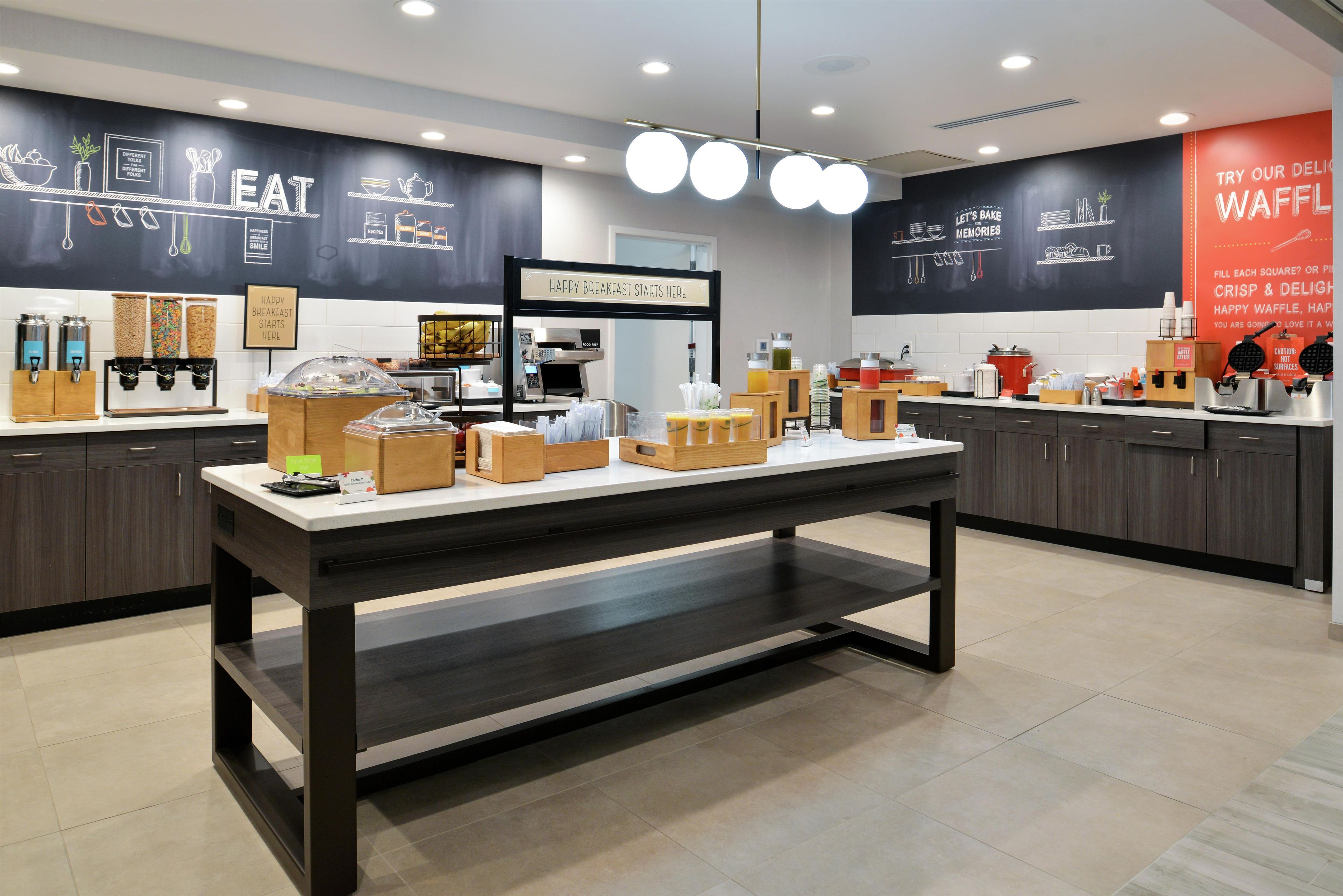 A breakfast buffet area with various food dispensers and a coffee machine.