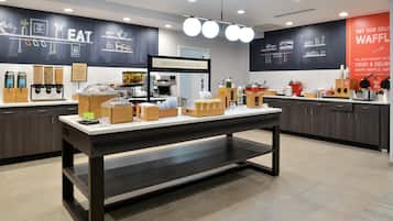 A breakfast buffet area with various food dispensers and a coffee machine.