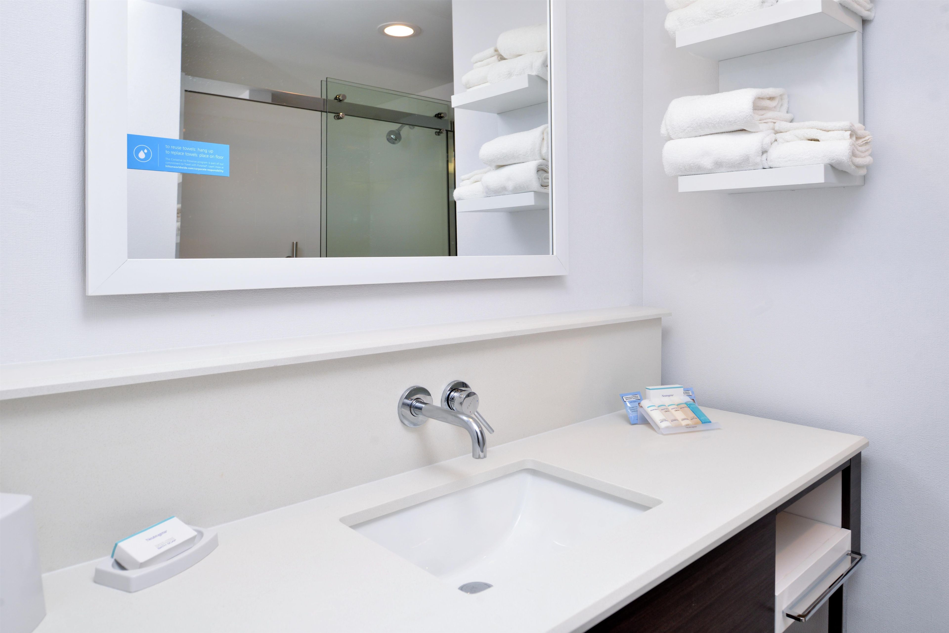 Un baño con un lavamanos blanco, un espejo y una cabina de ducha de vidrio.