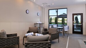 A modern lounge area with wicker furniture, a clock, and a view of the outdoors. - Hampton Inn Cedar Falls Downtown (Cedar Falls)