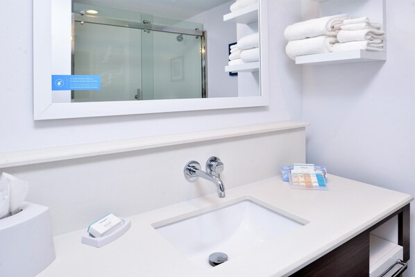 Une salle de bain avec un lavabo blanc, un miroir et un porte-serviettes.