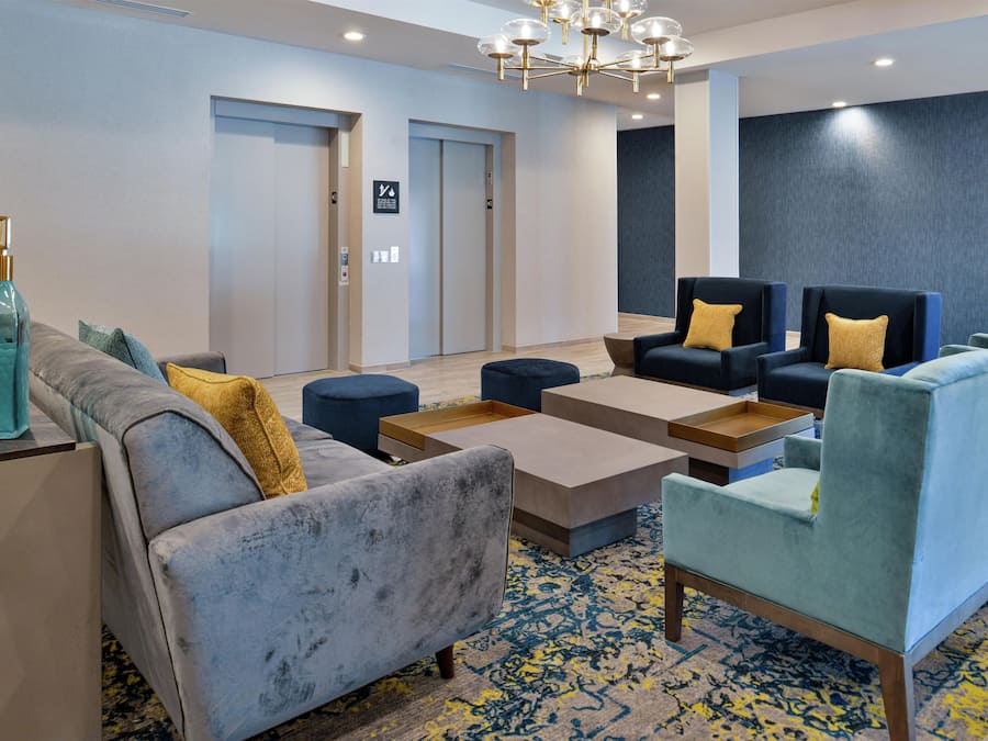 A hotel lobby with seating areas, a reception desk, and a chandelier.