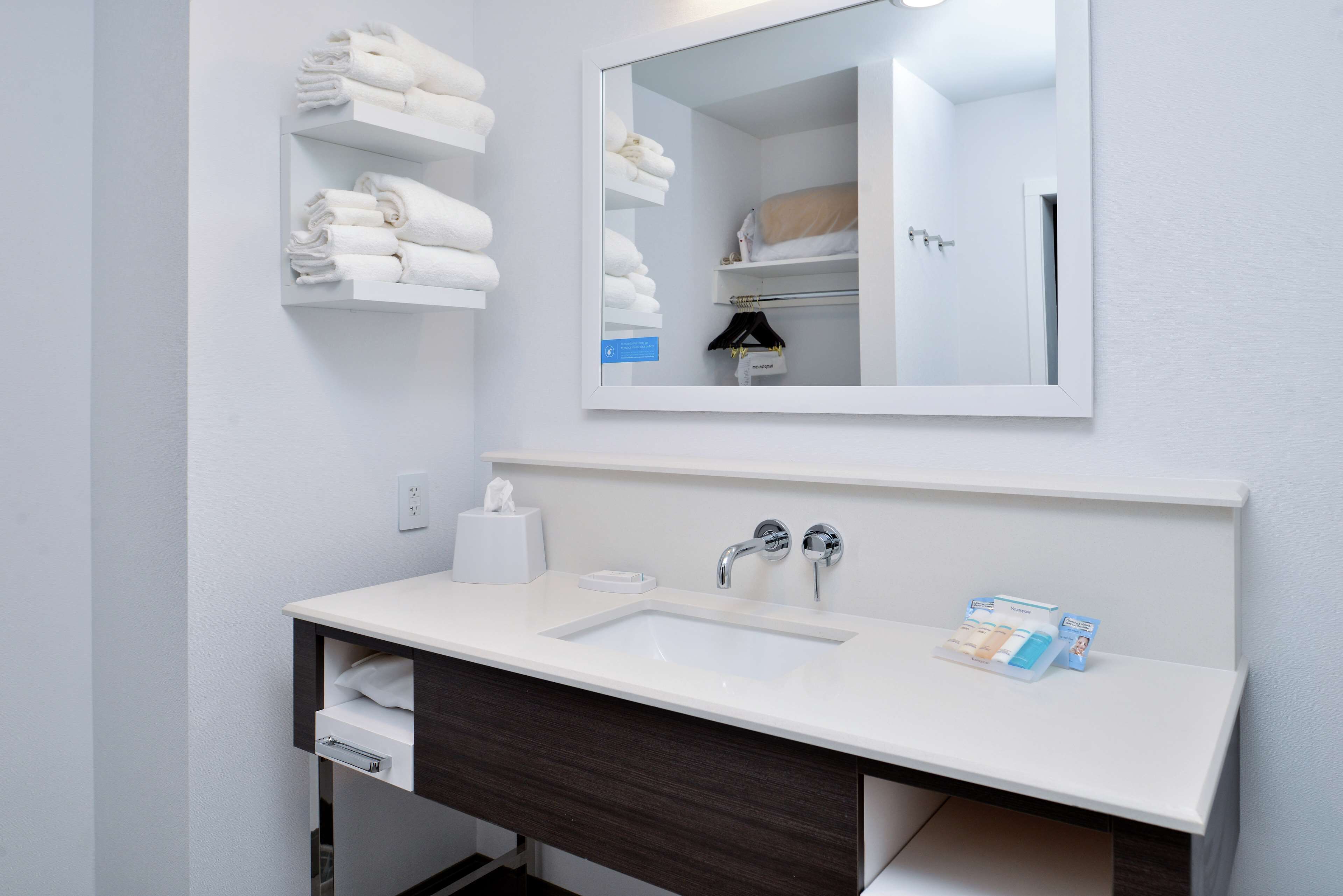 A modern bathroom with a white sink, dark wood vanity, and a mirror above the sink.