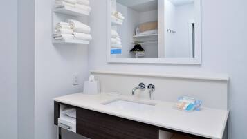 A modern bathroom with a white sink, dark wood vanity, and a mirror above the sink.