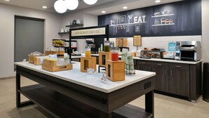 A breakfast area with a counter, coffee machine, and various food items. - Hampton Inn Cedar Falls Downtown (Cedar Falls)