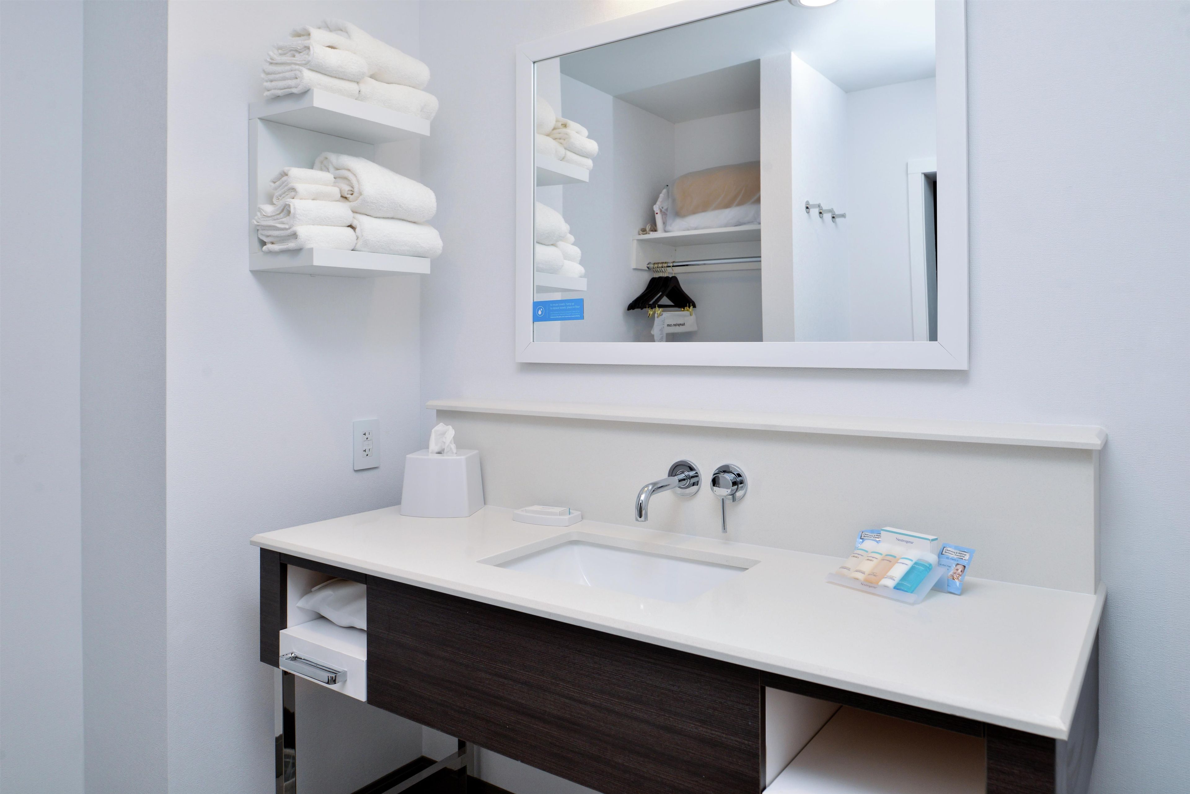 Un baño moderno con un lavamanos blanco, un espejo y un perchero para toallas.
