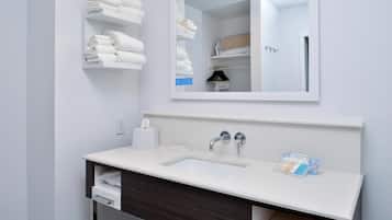 Un baño moderno con un lavamanos blanco, un espejo y un perchero para toallas.
