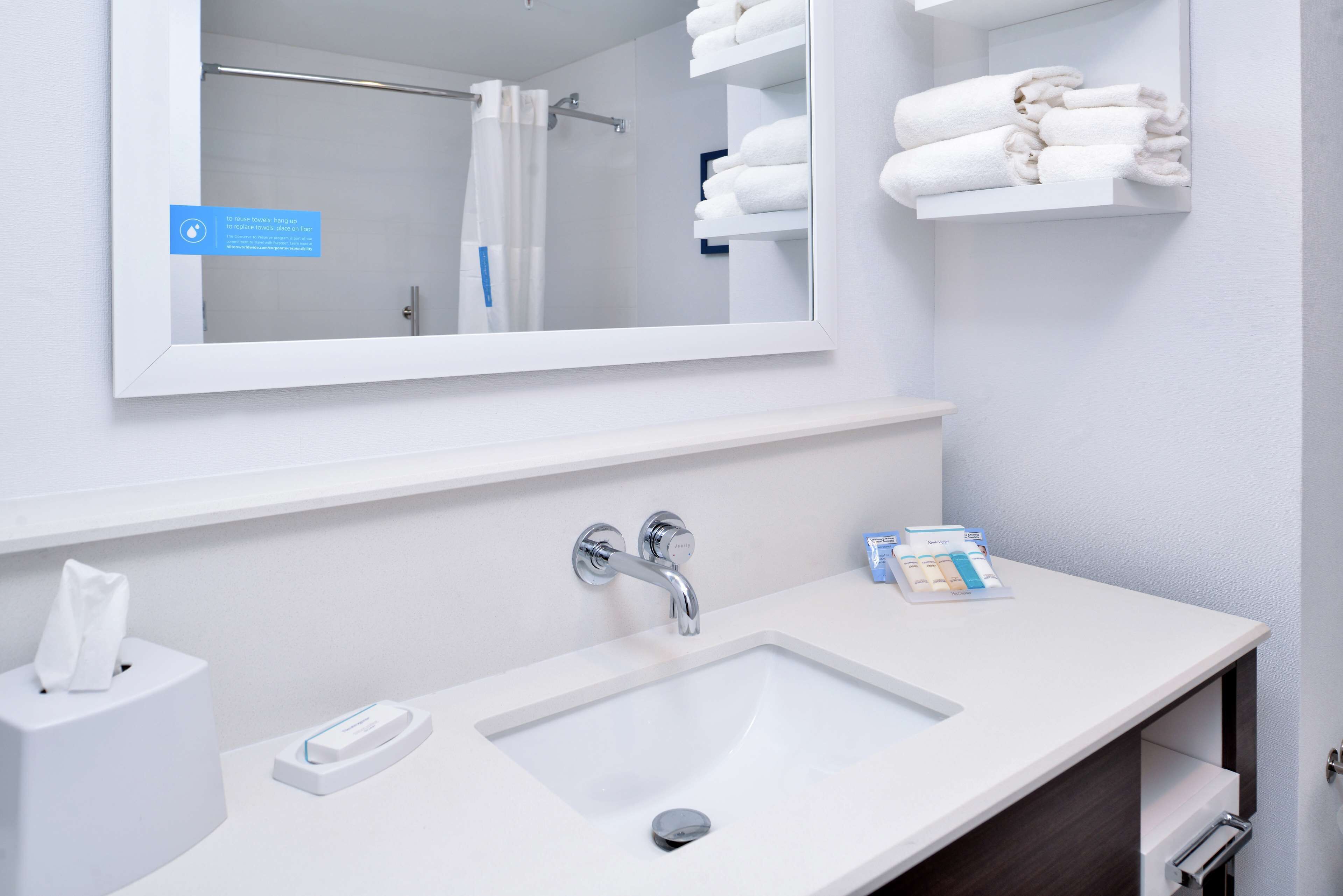 A modern bathroom with a white sink, a mirror, and a towel rack.
