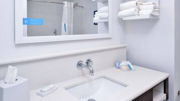 A modern bathroom with a white sink, a mirror, and a towel rack.
