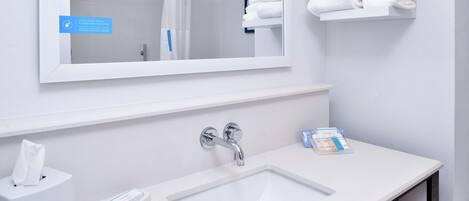 A modern bathroom with a white sink, a mirror, and a towel rack.