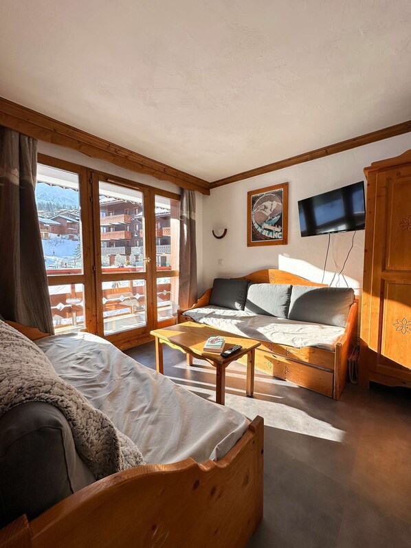 A cozy room with a bed, a sofa, a wooden table, and a TV.