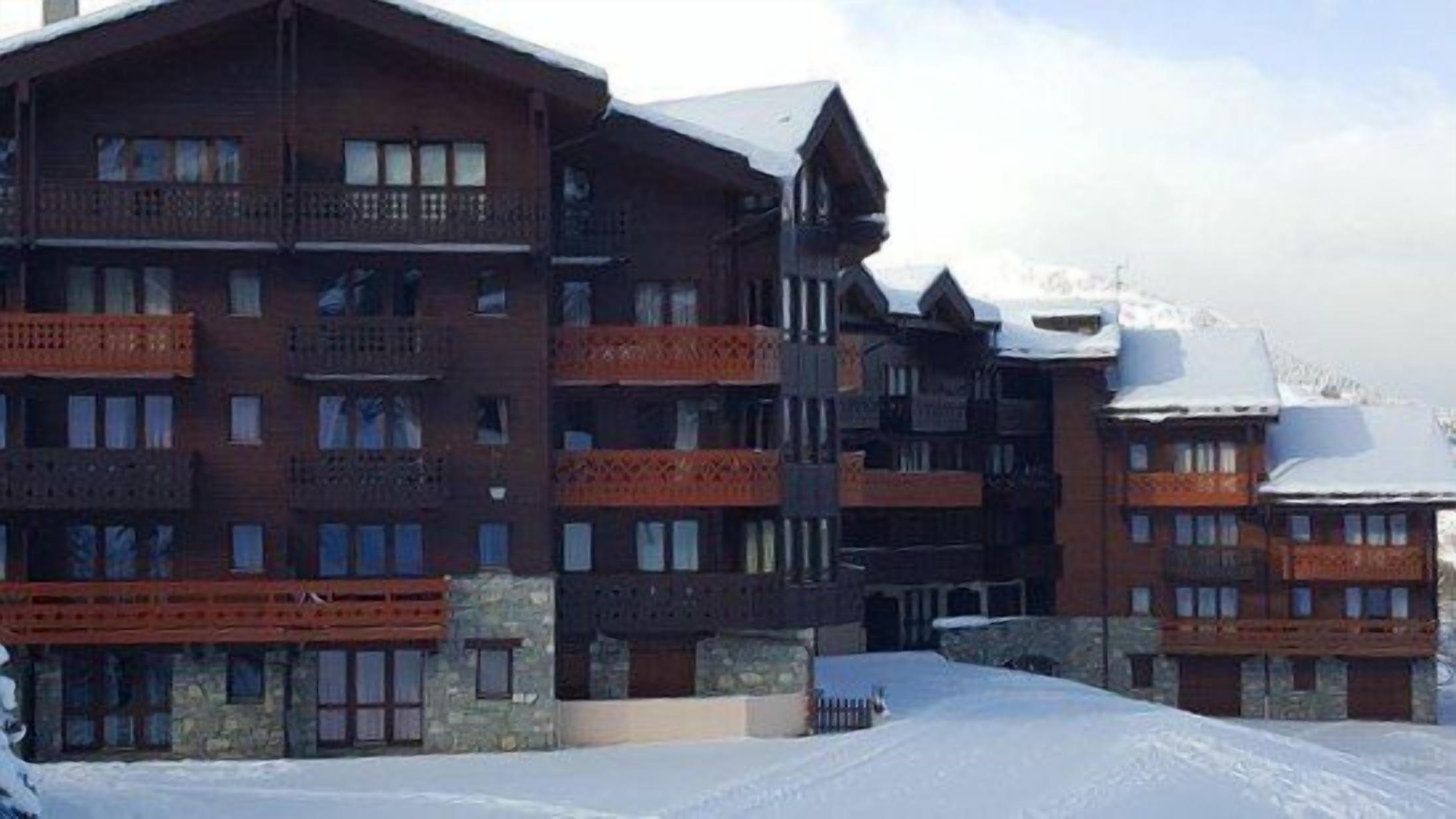 A multi-story hotel with balconies, stone facade, and snow-covered surroundings.