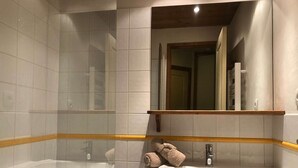 A bathroom with two sinks, a bathtub, and a mirror.