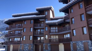 Ein mehrstöckiges Hotel mit Balkonen, Steinverzierungen und einem verschneiten Berg im Hintergrund.