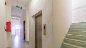 A hallway with a marble wall, an elevator, and a staircase. - OYO 238 Luxury Motel (Da Nang)
