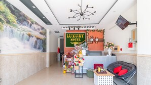 A lobby with a waterfall mural, a reception desk, a chair, and a staircase. - OYO 238 Luxury Motel (Da Nang)