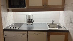 A kitchen with a microwave, coffee maker, stove, sink, and dishwasher. - Bûche 13 - Cosy studio with movable partition (LES AVANCHERS VALMOREL)