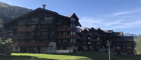 A multi-story hotel with balconies, stone facade, and a view of the surrounding landscape.